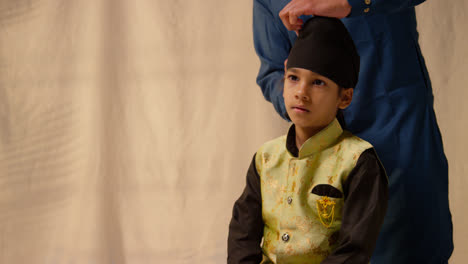 Foto-De-Estudio-De-Un-Padre-Atando-Un-Turbante-En-La-Cabeza-De-Su-Hijo-Sikh-Que-Lleva-Un-Chaleco-Tradicional,-Como-Se-Muestra-En-La-Secuencia,-Parte-3-De-10